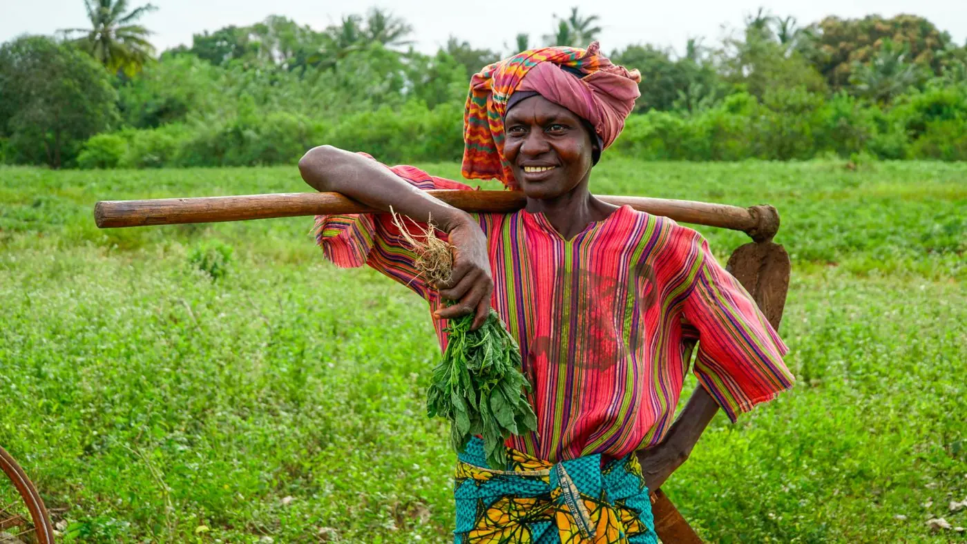 Farmer standing in a field beside sacks of harvested crops