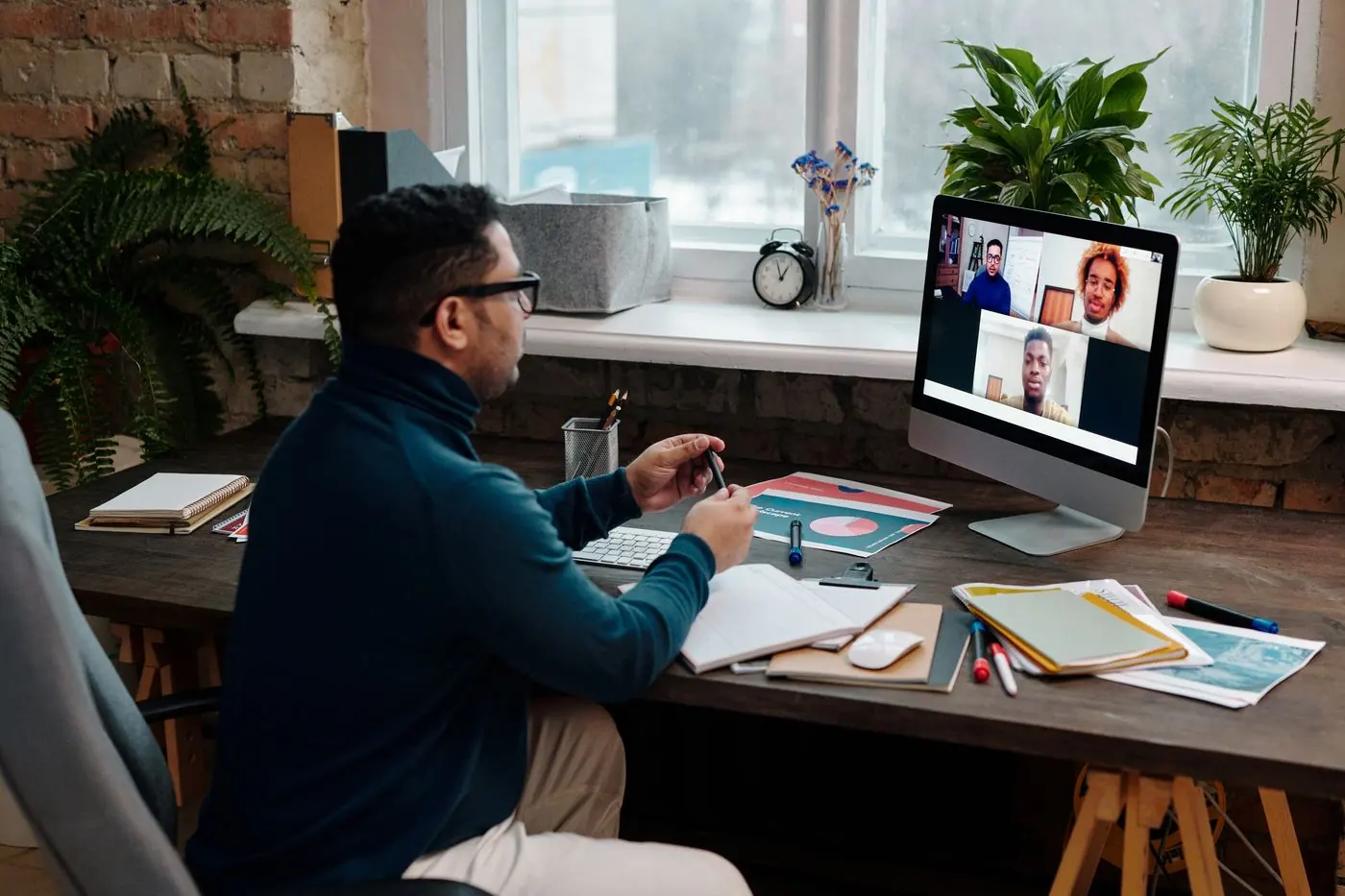 Teacher talking to students over a video call at a desk